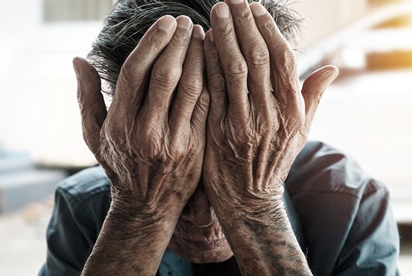 old man covering face with his hands