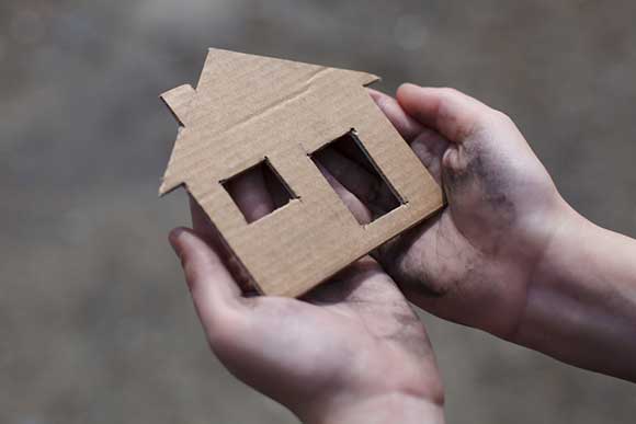 Boy with a cardboard cut out of a house