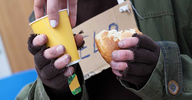 Woman giving tea to homeless man