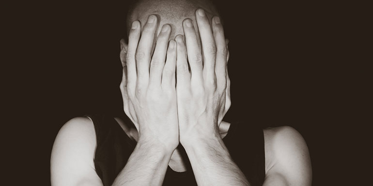 Man living with mental illness with face in his hands