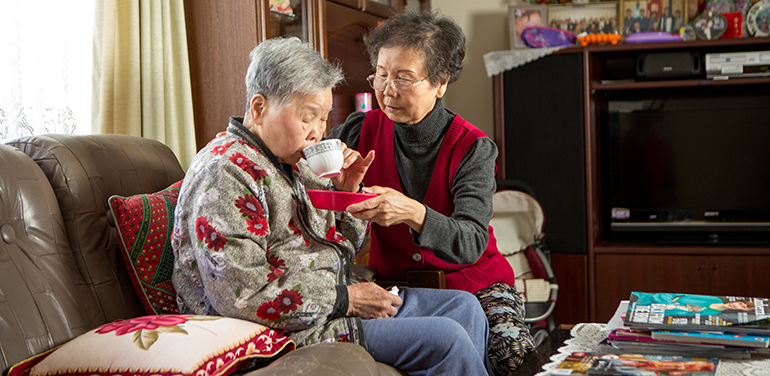 Woman helping her mum have a drink