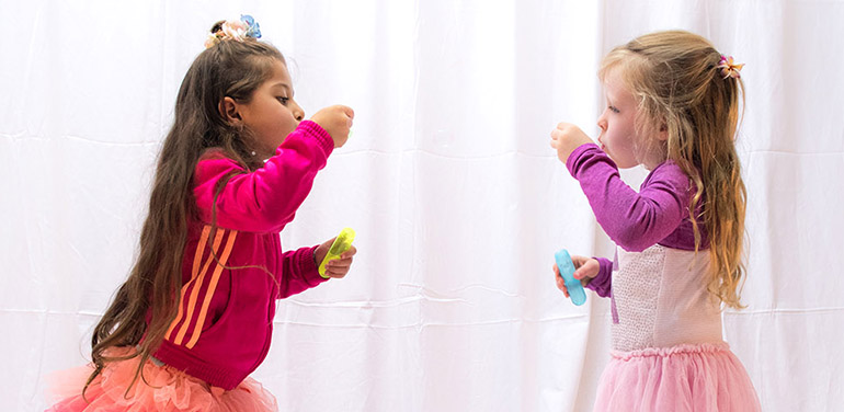 Two girls blowing bubbles towards each other