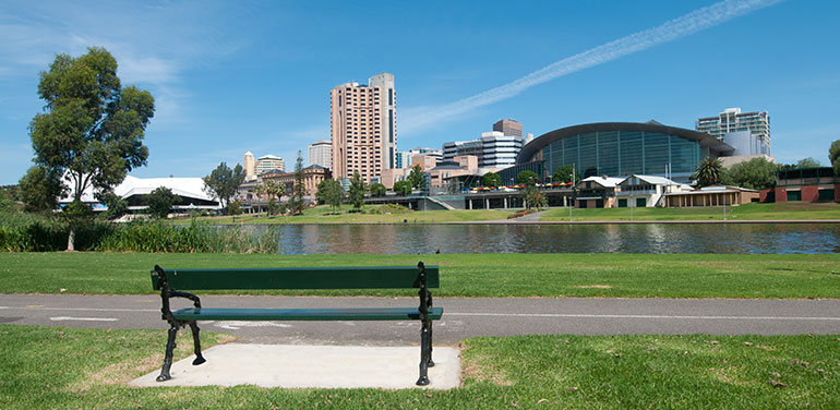 Empty park bench with Adelaide skyline in the background