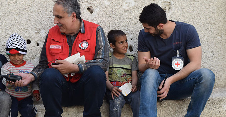 Red Cross workers speak with children in Syria