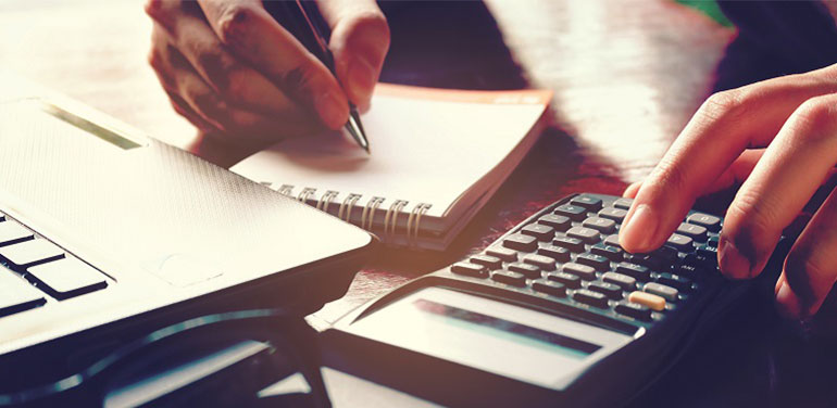 Man working on calculator and writing in notebook