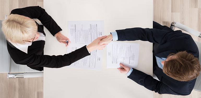 Overhead shot of two people shaking hands at job interview