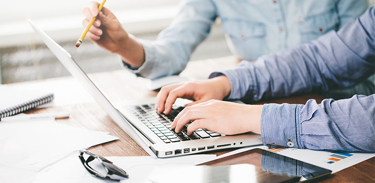 Two people discussing something on a laptop