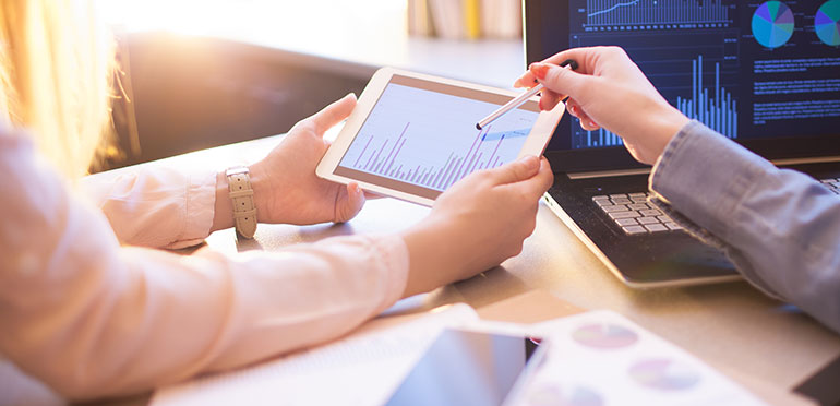 Two women looking at graphs.