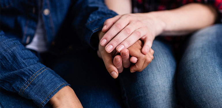 women holding hands, consoling each other