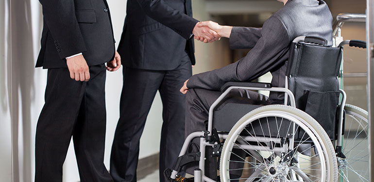 Man in wheelchair shaking hands with men in suits