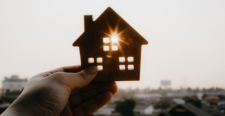 hand holding cardboard house up to window