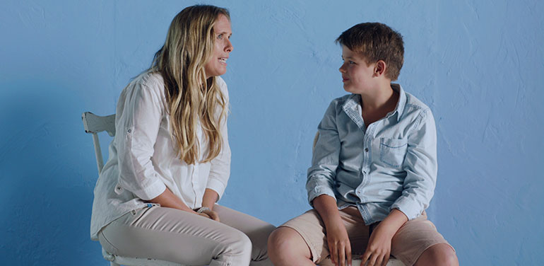 Woman and boy talking against blue backround