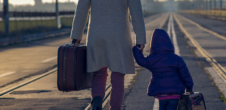 woman and child holding hands walking along road