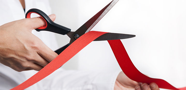 lady cutting red tape with scissors