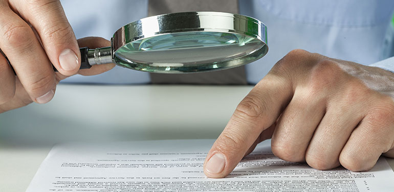 person reviewing document with a magnifying glass