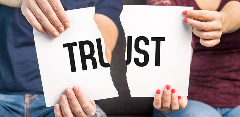 two people tearing piece of paper with the word trust on it