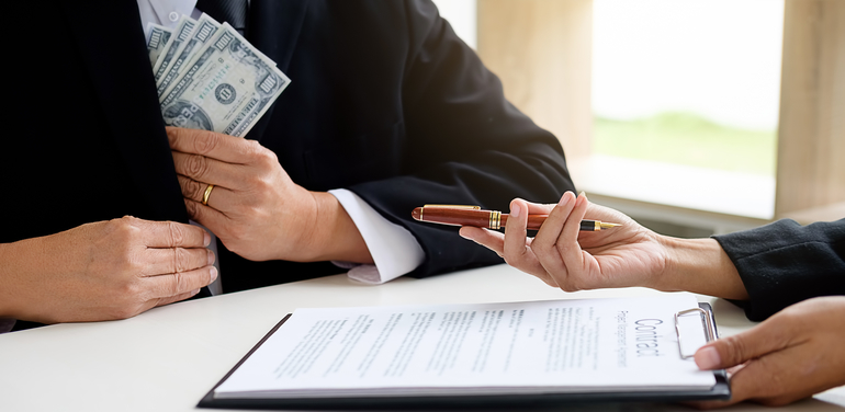 Businessman in suit hides money. A bribe in the form of dollar bills.