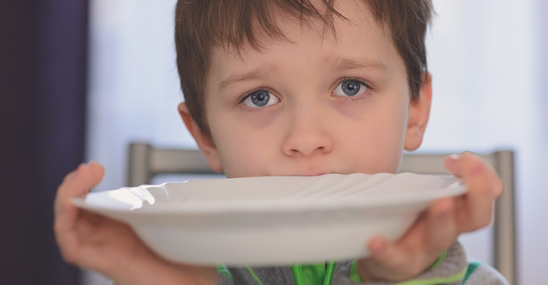 sad child with an empty plate.