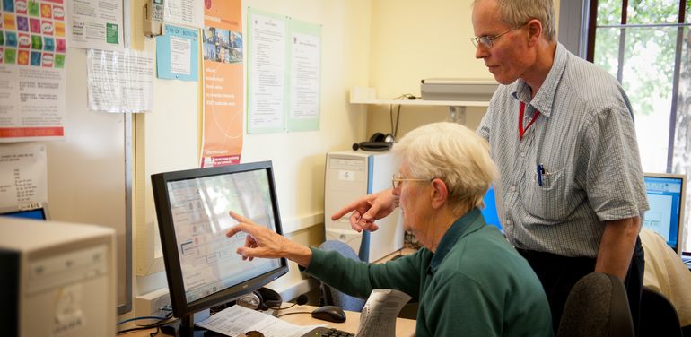 Man helping lady on the computer