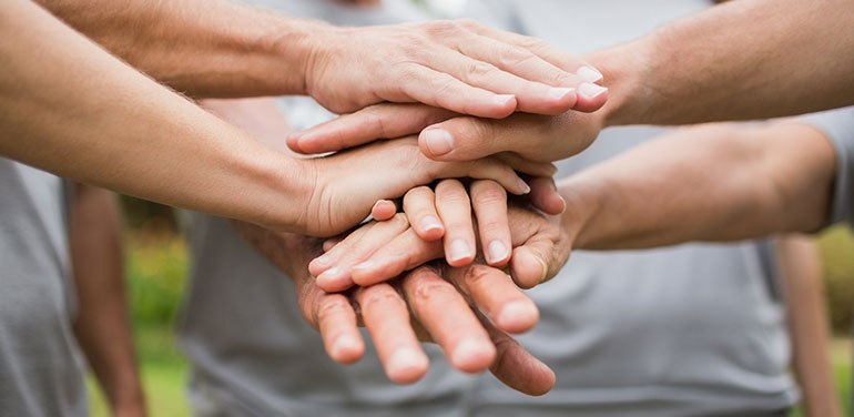 Group of volunteers with their hands in the middle