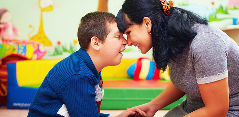 Mother and son with disability with their heads together