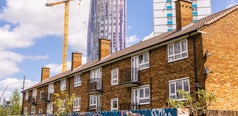 Row of houses with skyscrapers being built behind