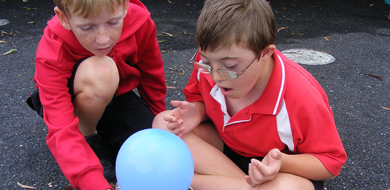 Two children playing with a balloon.