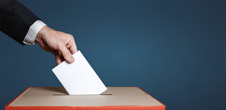 person putting ballot in box