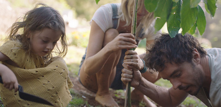 Still from the doco 2040 showing Gameau planting a tree with his wife and daughter.