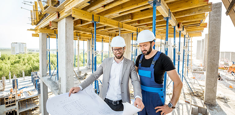 Engineer standing with builder supervising the construction process of a house