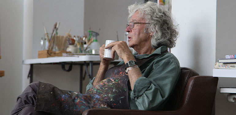 Michael Leunig drinking a cup of tea in his studio.