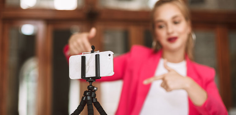 A woman in a pink jacket recording a video diary on her phone