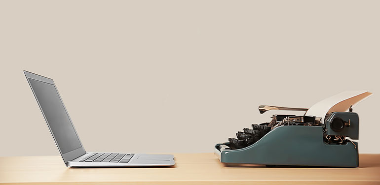 Old typewriter and laptop on table