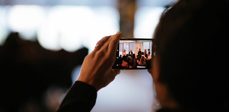 Image of someone taking a photo on their phone of a panel at the last Social innovation Summit