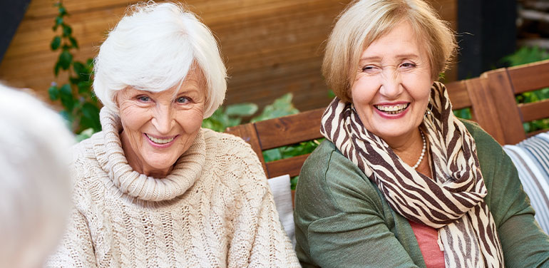 two older women talking and smiling in a group