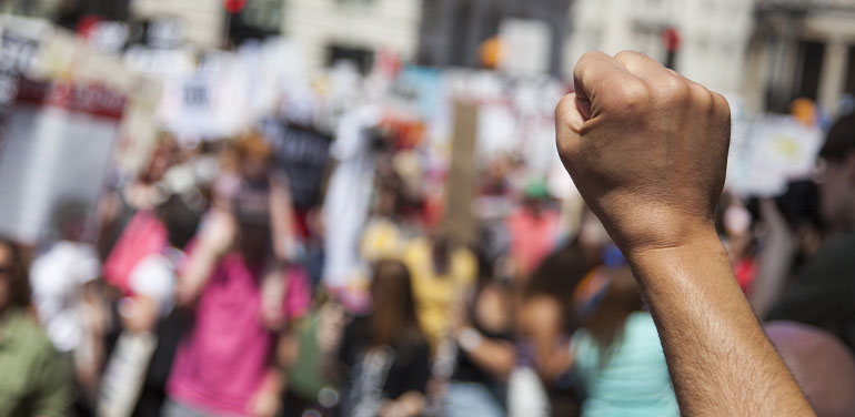 person raising fist in the air at a protest