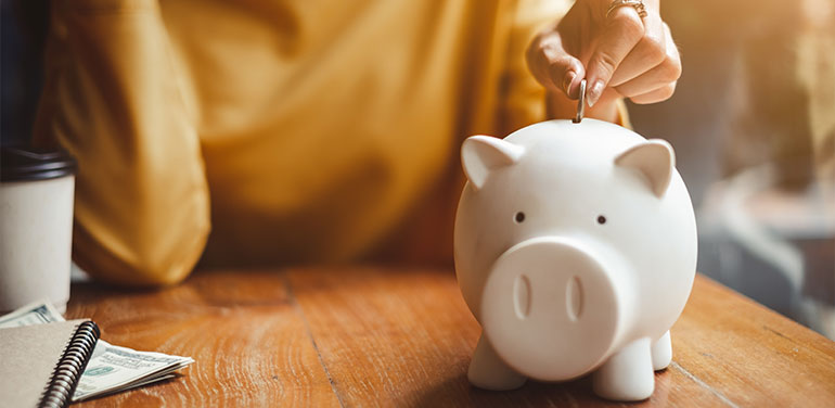 woman putting a coin in a piggy bank