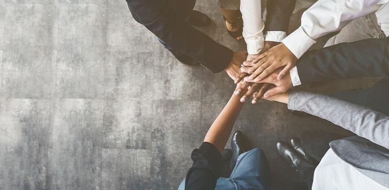 group of business people with hands together in the middle