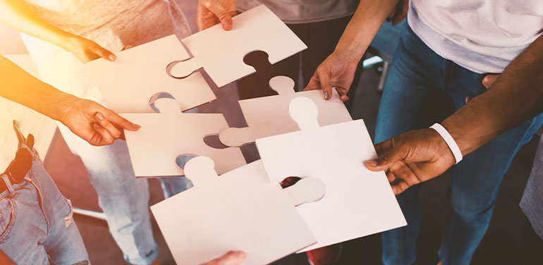 Group of people putting together jigsaw pieces