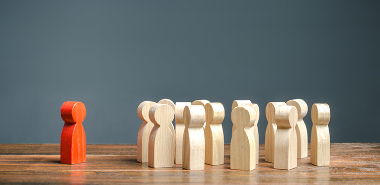 red wooden figure standing in front of white wooden figures