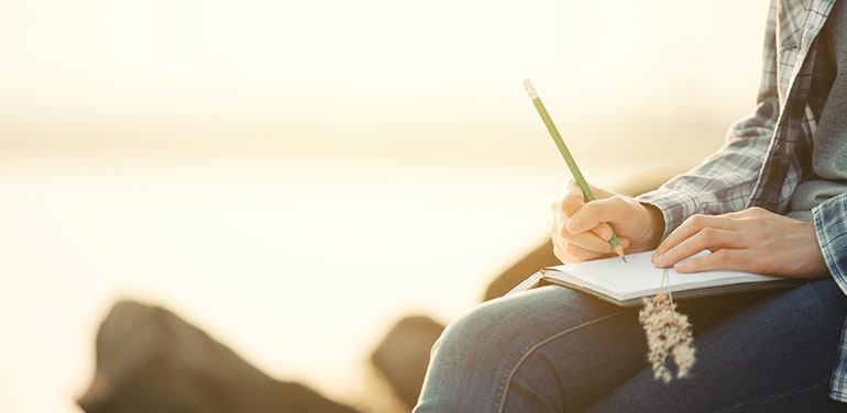 Person sitting outside writing a list