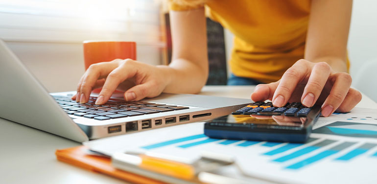 woman using a laptop and a calculator