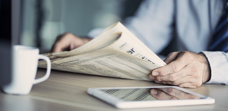 close up of man's hands holding a newspaper