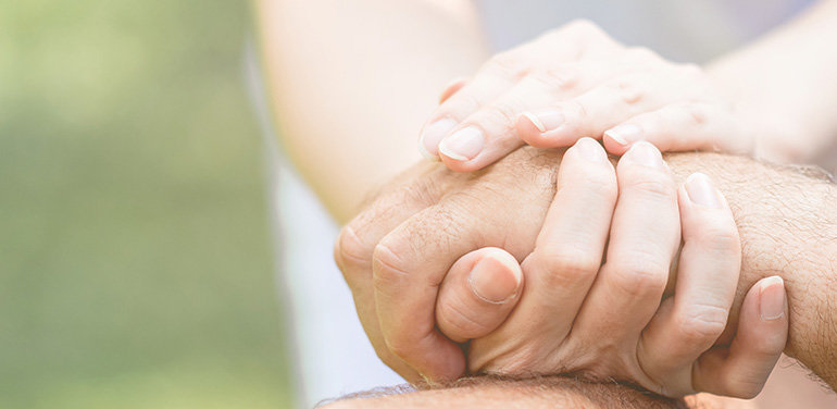 close up of carer holding patient's hands in her hands