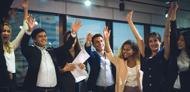 group of smiling business people with their hands in the air