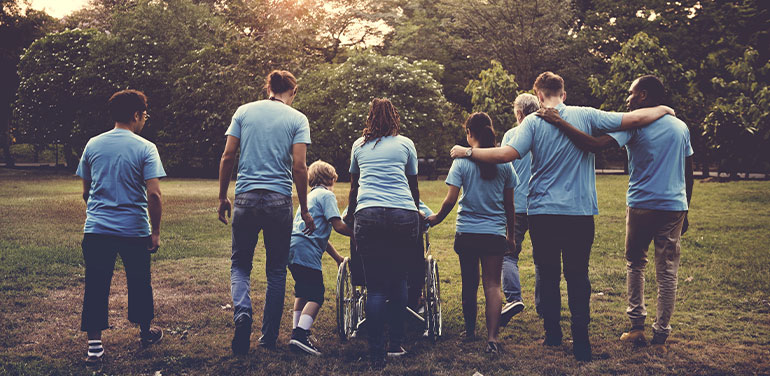 group of people including a person in a wheelchair all wearing blue tshirts and walking away from the camera