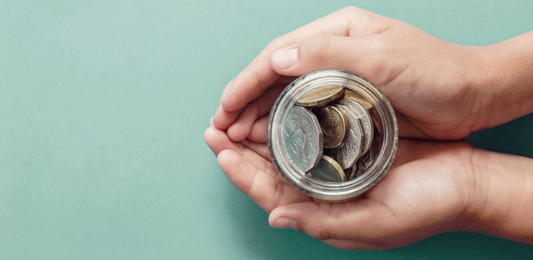 hands cupping a jar with coins in it