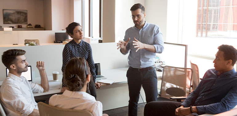 leader talking to his team of four people sitting in a circle