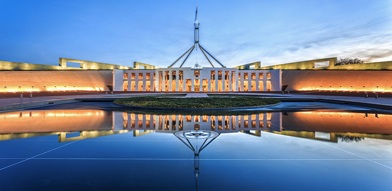 Parliament House in Canberra at night. Silhouette of building reflected in water.