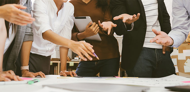 group of people standing around a desk planning